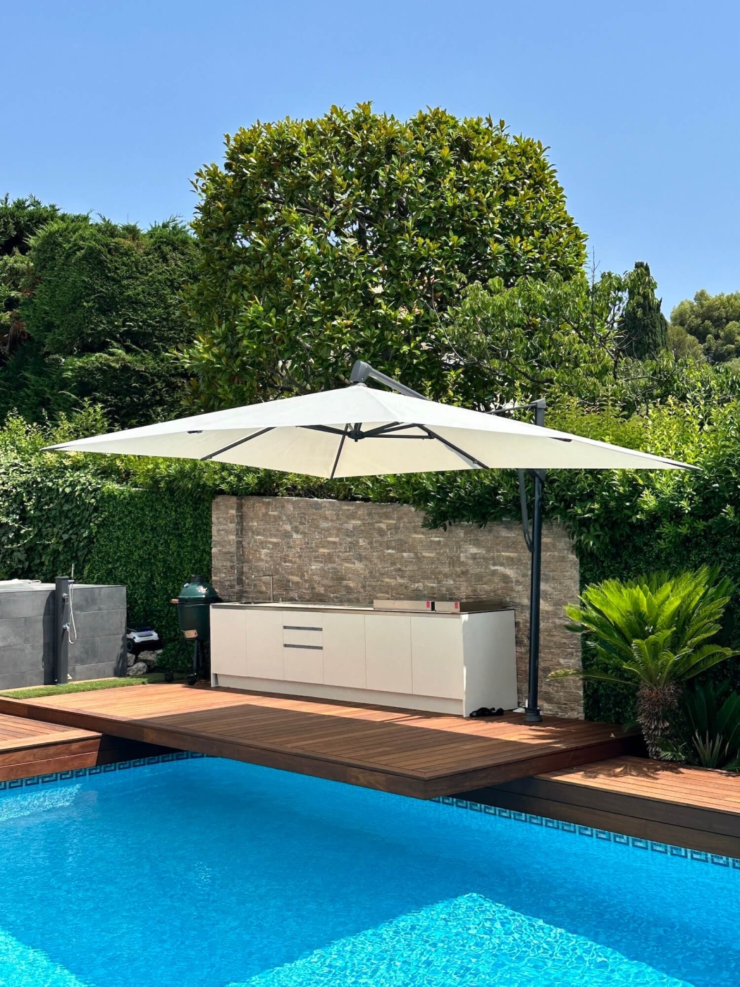 Aménagement d'un parasol Sombrano à côté d'une cuisine sur-mesure pour l'extérieur d'une maison située sur la Côte d'Azur