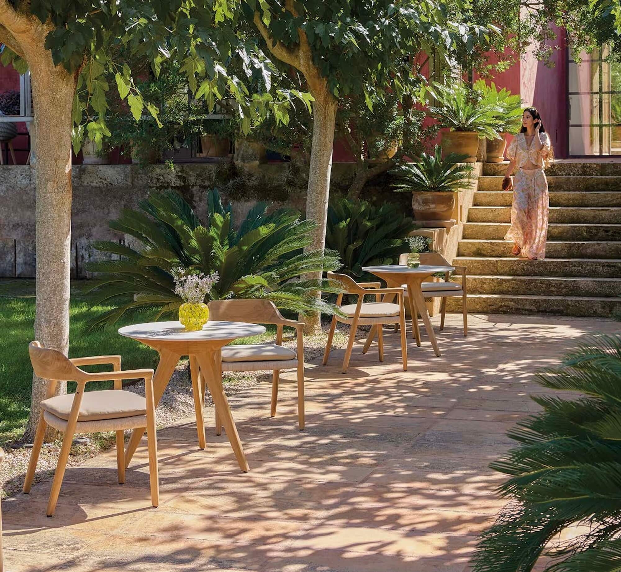 Chaises de repas en bois teck, et tissu beige aux lignes arrondies avec des tables rondes à Cannes 